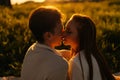 Close-up silhouette view of loving young couple sitting hugging and kissing on beautiful meadow with green grass having Royalty Free Stock Photo