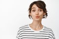 Close up of silly and cute brunette girl pucker lips, funny kissing face, looking coy at camera, standing in t-shirt