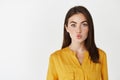 Close-up of silly and cute girl pucker lips, making kissing shape and looking at camera, standing over white background Royalty Free Stock Photo