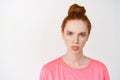 Close-up of silly redhead teen girl showing tongue and frowning, standing against white background angry Royalty Free Stock Photo