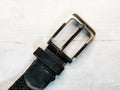 Close-up of a silver buckle from a trouser belt on a wooden tabletop background