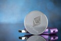 Close up silver digital cruptocurrency coin ethereum with hardware wallet on blue background with copy space. Royalty Free Stock Photo