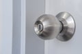 A silver doorknob mounted on a white door. Royalty Free Stock Photo