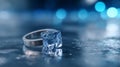 Close-up of a silver ring with a melting ice cube on a wet reflective surface with blue bokeh background Royalty Free Stock Photo