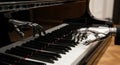 Close-up of silver robotic hands playing a piano keyboard with black and white keys from a low angle perspective in a room with a Royalty Free Stock Photo
