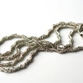 A close-up of a silver rope chain on a white surface. The chain features an intricate, twisted Royalty Free Stock Photo