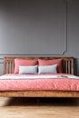 Close-up of a simple bed with wooden bedhead and pink sheets in