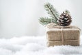 close-up simple burlap christmas gift box wrapped with twine and a small pinecone placed on a white table with a soft texture with Royalty Free Stock Photo