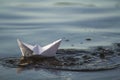 Close-up of simple small white origami paper boat floating in blue clear river or sea water under bright summer sky. Beauty of nat Royalty Free Stock Photo