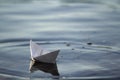 Close-up of simple small white origami paper boat floating quietly in blue clear river or sea water under bright summer sky. Freed Royalty Free Stock Photo