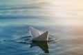 Close-up of simple small white origami paper boat floating quietly in blue clear river or sea water under bright summer sky. Royalty Free Stock Photo