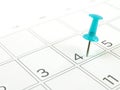 close-up single blue plastic pushpin tacking in 4th of july on schedule grid of desk calendar page