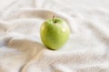 Close-up of single green juicy apple on the table with white tablecloth. Food photography using natural window light. Eating green Royalty Free Stock Photo