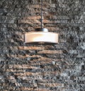 Close up of Single Modern Style Illuminated Lamp Hanged from The Ceiling Over The Vintage Style Stone Brick Pattern