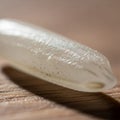 Close-up of a single rice grain on a wooden surface. The grain is translucent with a Royalty Free Stock Photo