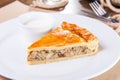 Close up of a single slice of chicken and mushroom pie with sauce on the white plate on the restaurant served table. Selective foc