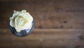 Close up of single white rose in a blue vase on a Pine wood as rustic background