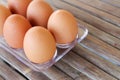 close up Six brown eggs in plastic box on bamboo table with one broken boiled egg, top view Royalty Free Stock Photo