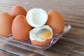 close up Six brown eggs in plastic box on bamboo table with one broken boiled egg, top view Royalty Free Stock Photo