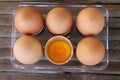 close up Six brown eggs in plastic box on bamboo table with one broken egg, top view Royalty Free Stock Photo