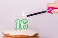 Man`s hand lighting sixteenth birthday candles on rustic vanilla layer cake Royalty Free Stock Photo