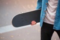 Close-up of a skateboarder holding a skateboard in hands.