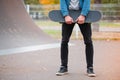 Close-up of a skateboarder holding a skateboard in hands.