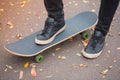 Close-up of a skateboarder`s foot in black sneakers.