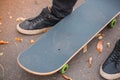 Close-up of a skateboarder`s foot in black sneakers.