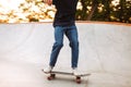 Close up skater boy in T-shirt and jeans practicing at modern skate park