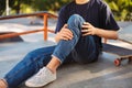 Close up skater holding his painful leg with skateboard near at skatepark isolated Royalty Free Stock Photo