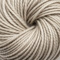 Close-up of a skein of yarn tightly wound in a circular pattern. The yarn is beige, with a Royalty Free Stock Photo
