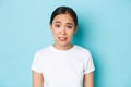 Close-up of skeptical and indecisive young asian woman frowning and grimacing with judgemental, hesitant expression Royalty Free Stock Photo