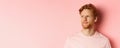 Close up of skeptical and unamused european man, smirk with judgemental face, looking left at banner, standing over pink Royalty Free Stock Photo