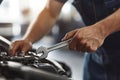 Close-up of skilled hands gripping a wrench as they make adjustments on a car engine. The vibrant workshop setting Royalty Free Stock Photo