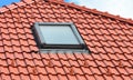 A close-up on a skylight installation on the ceramic tiled, clay tiled red rooftop