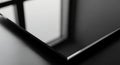 Close-up of a sleek, black surface with polished, sharp edges, reflecting nearby window frames. The Royalty Free Stock Photo