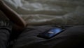 Close up of sleeping man being woken up by his phone lying on the bed. Concept. Male hand trying to turn off the alarm Royalty Free Stock Photo