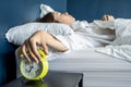 Close up sleepy woman stretching hand to ringing alarm willing turn it off, pressing button, woken by signal, lying under blanket Royalty Free Stock Photo