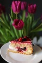 Close up of slice of berry cake on a white plate near beautiful tulips flowers. holiday. birthday cake Royalty Free Stock Photo