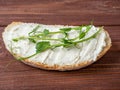 Close-up of a slice of bread spread with cottage cheese and decorated with fresh micro greenery. Brown wooden background. Top view Royalty Free Stock Photo