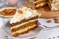 Close-up the slice of carrot cake with almonds on a saucer and a fork near.