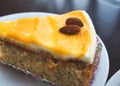 Close-up of a slice of carrot cake with orange icing and almonds on top Royalty Free Stock Photo