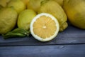 Close up of a Slice of lemon along with a group of lemons on a wood table