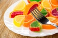 Close up of slice of marmalade on fork, multicolor marmalade in form slices of lemon in plate on table Royalty Free Stock Photo