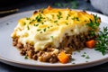 Close-up of a slice of piping hot Shepherds Pie on a white plate with a dollop of sour cream on top