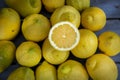 Close up of a Slice of lemon along with a group of lemons on a wood table