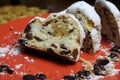 Close up of sliced christstollen with raisins, white powdered sugar and marzipan on red plate