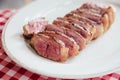 Close up Sliced medium rare charcoal grilled boneless wagyu Top Loin steak in white plate on red and white pattern tablecloth