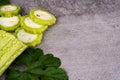 Close-up of sliced and whole bitter melons with leaves on textured surface Royalty Free Stock Photo